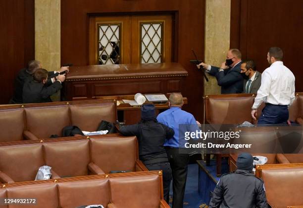 Capitol police officers point their guns at a door that was vandalized in the House Chamber during a joint session of Congress on January 06, 2021 in...
