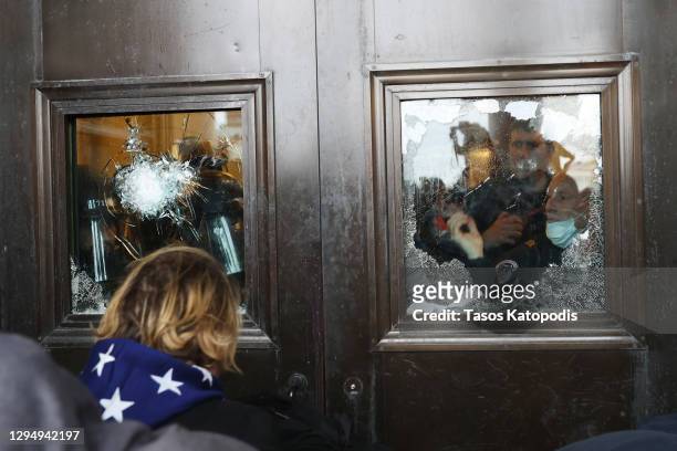 Capitol police officer looks out of a broken window as protesters gather on the U.S. Capitol Building on January 06, 2021 in Washington, DC....