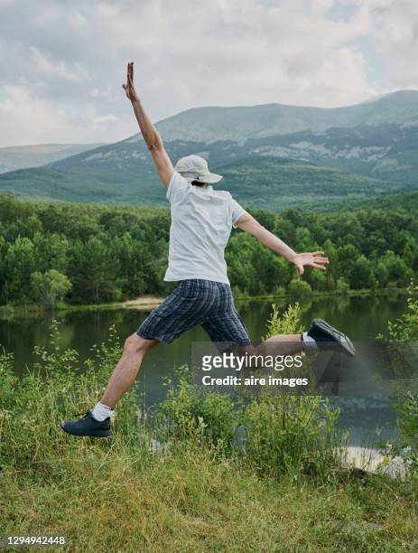 man jumping backwards next to a mountain and lake landscape. moncayo montain, zaragoza, spain - leap forward stock pictures, royalty-free photos & images