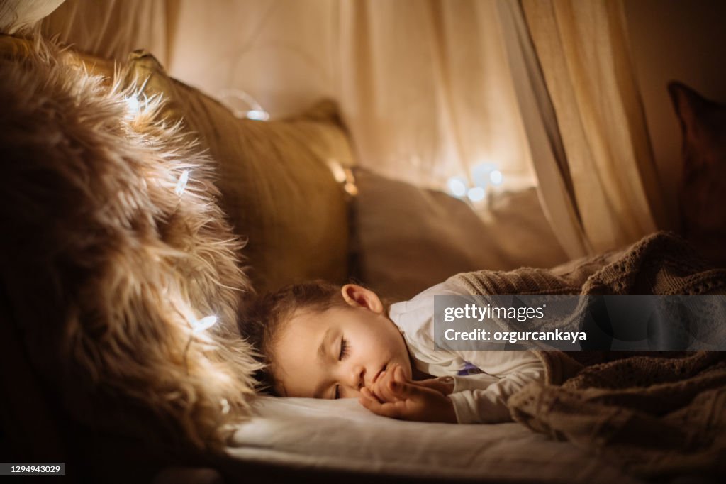Pequeña niña en edad preescolar durmiendo en una cama cómoda