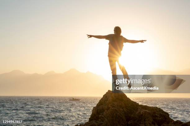hiker relaxes on sunny coastal ciff at sunrise - sunrise over water stock pictures, royalty-free photos & images