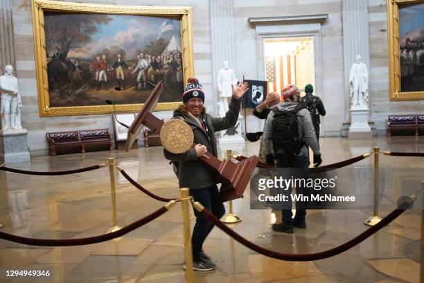 Pro-Trump protester carries the lectern of U.S. Speaker of the House Nancy Pelosi through the Rotunda of the U.S. Capitol Building after a pro-Trump...