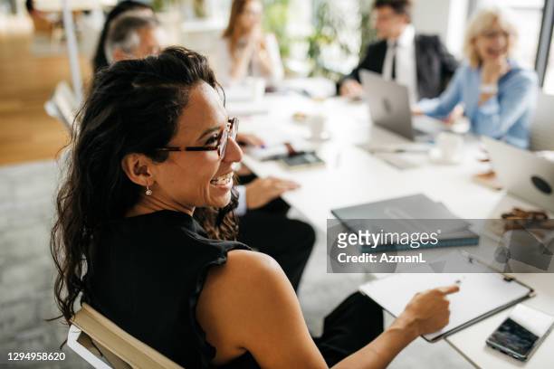 candid close-up of hispanic businesswoman in office meeting - multiracial group foto e immagini stock