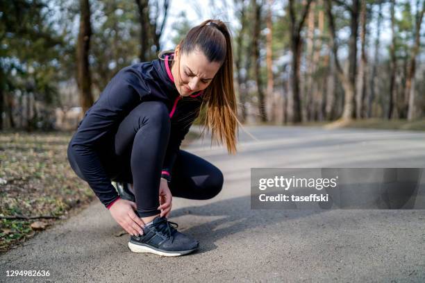 runner girl is holding her injured leg - injured runner stock pictures, royalty-free photos & images