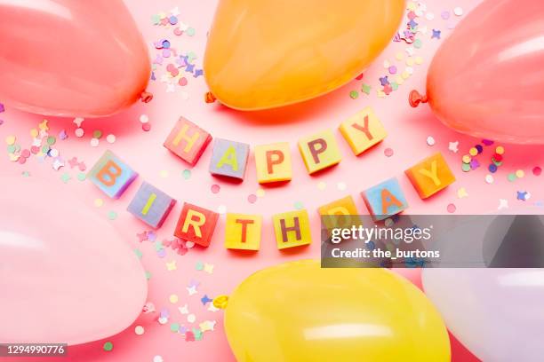 high angle view of colorful happy birthday letters and balloons in heart shape on pink background - birthday balloons confetti stock pictures, royalty-free photos & images