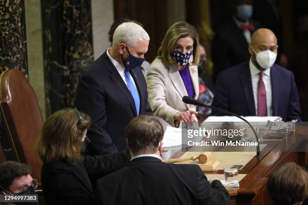 Vice President Mike Pence and U.S. Speaker of the House Nancy Pelosi look over documents in the House Chamber during a reconvening of a joint session...