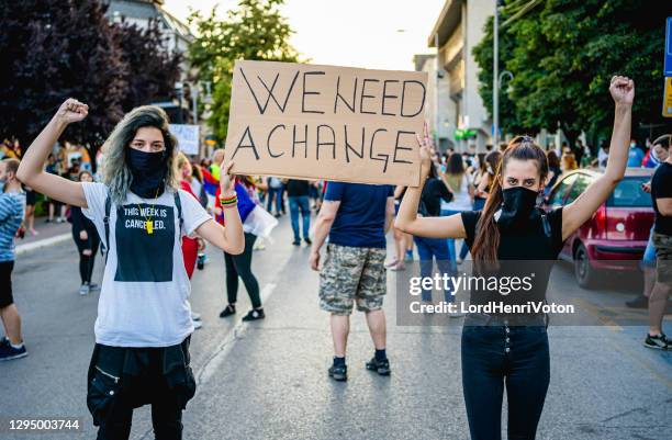 young protestant women holding a poster with text "we need a change" - protest banner stock pictures, royalty-free photos & images