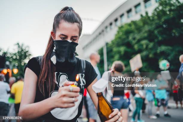 young female protester lights molotov cocktail - cocktail molotov stock pictures, royalty-free photos & images