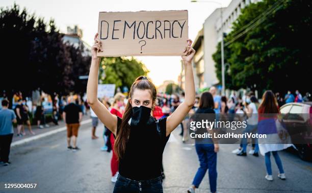 young woman protester holding placard with text "democracy?" - placard stock pictures, royalty-free photos & images