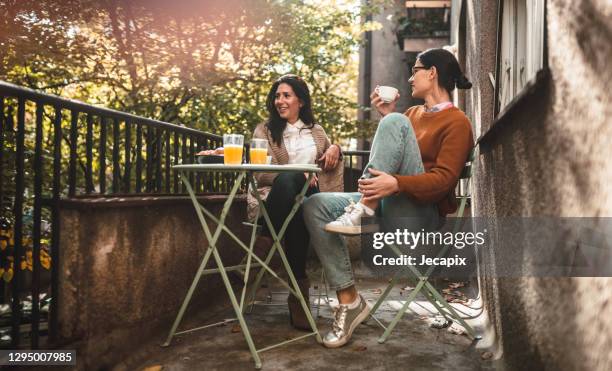 zwei junge frauen verbringen zeit zusammen auf der terrasse mit kaffee - nur frauen balkon stock-fotos und bilder