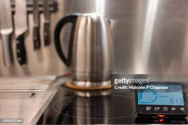home electricity smart meter in kitchen and stainless steel kettle. - smart kitchen stock pictures, royalty-free photos & images