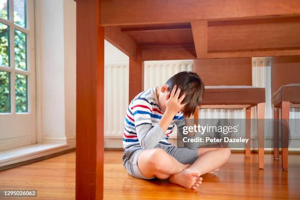 unhappy boy under table - crying child stock pictures, royalty-free photos & images