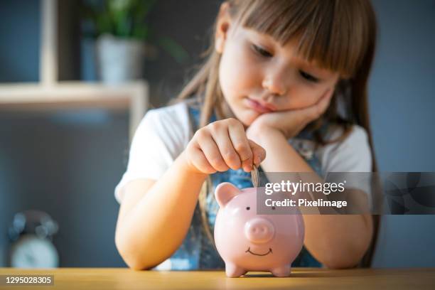 girl hand putting coin in piggy bank. save money and financial investment - childrens health fund benefit stock pictures, royalty-free photos & images