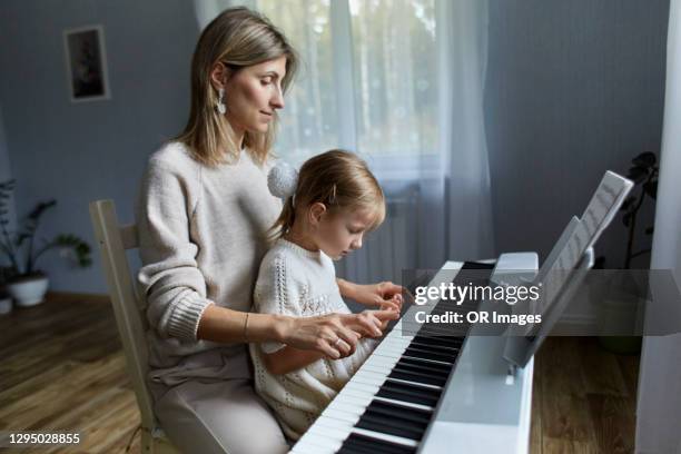 mother playing electric piano with daughter - electric piano fotografías e imágenes de stock