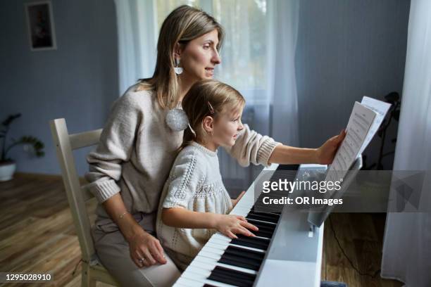 mother playing electric piano with daughter - electric piano stock pictures, royalty-free photos & images