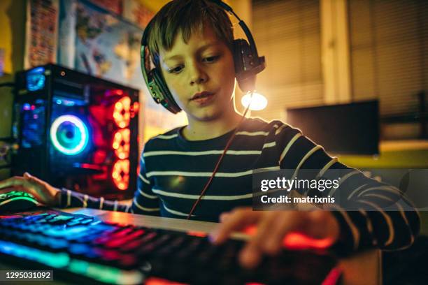 young boy playing games on a computer at home, during the pandemic. - teenage boy playing playstation stock pictures, royalty-free photos & images