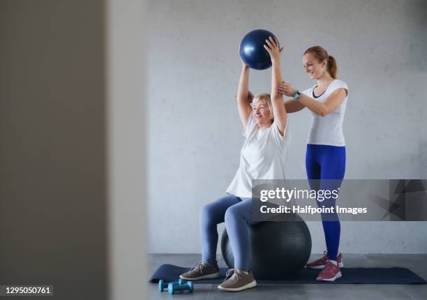 personal trainer helping senior woman to exercise, healthy lifestyle concept. - gym excercise ball stock pictures, royalty-free photos & images