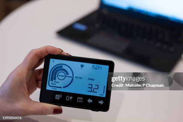 woman holding home smart meter at kitchen table with laptop - electricity meter stock pictures, royalty-free photos & images