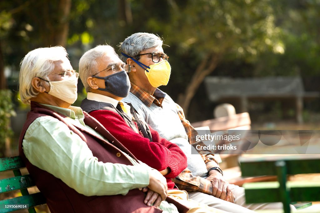 Senior men wearing face masks while relaxing at park