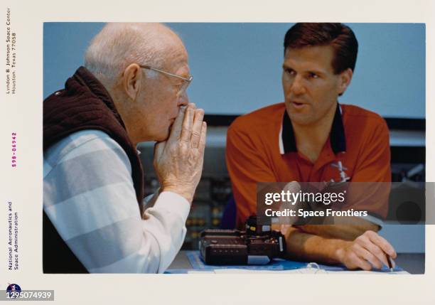 American NASA astronaut and politician John Glenn listens to instructions about camera usage from crew trainer David Williams during a training...