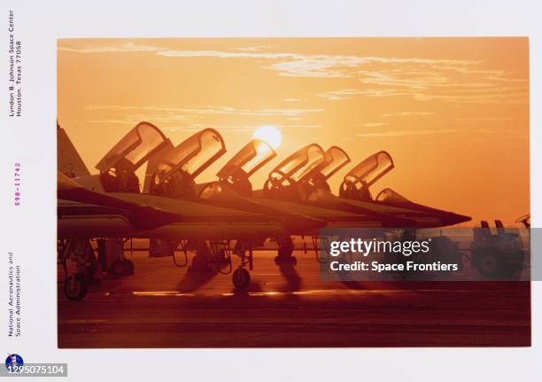 The sun sets over a row of T-38 Talon aircraft, each with the canopy in an upright position, at Kennedy Space Center on Merritt Island, Florida,...