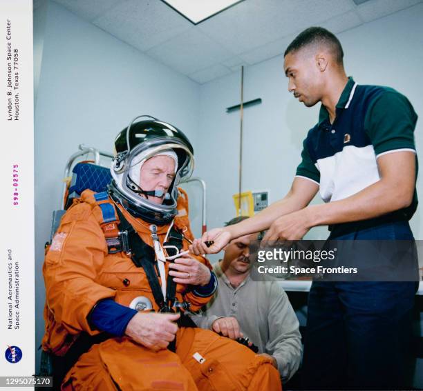 American NASA astronaut and politician John Glenn , assisted by Boeing's Lloyd Armintor and Lockheed's Carlous Gillis during a suit fit check at the...