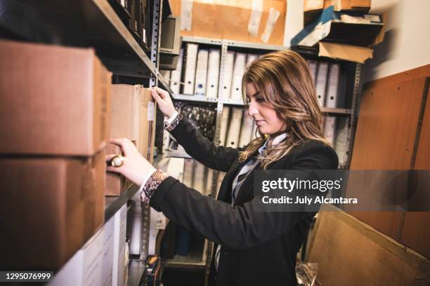 attractive woman searches archive basement for old documentation and files - archives stock pictures, royalty-free photos & images