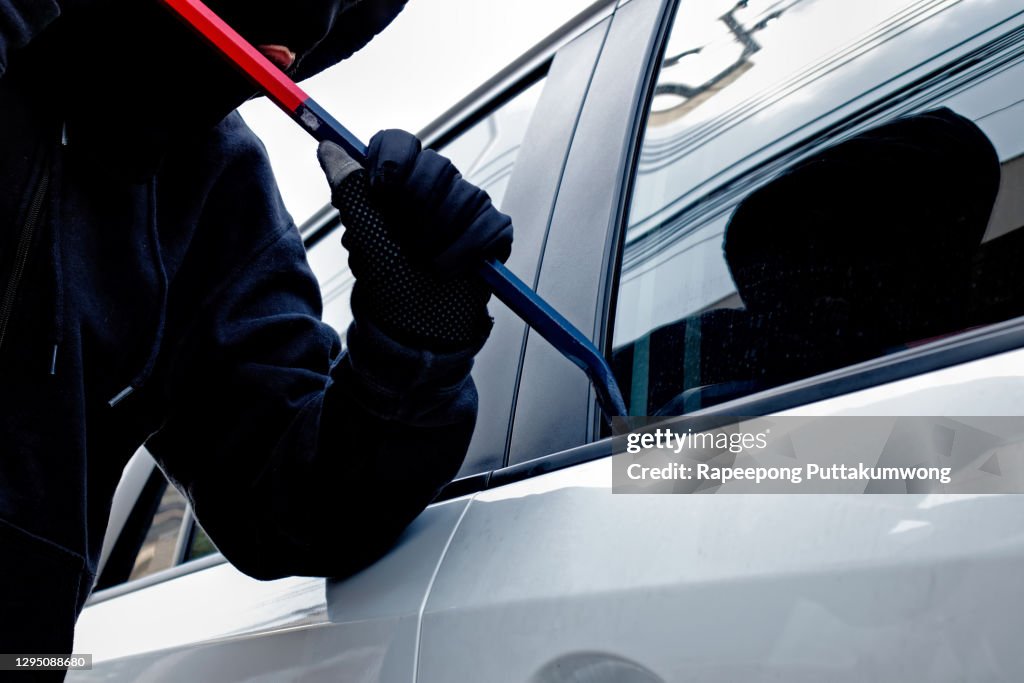 Masked burglar trying to get into a car