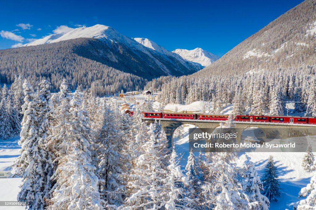 Red Bernina Express train in the snowy landscape, Chapella, Switzerland
