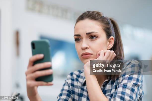 close up of a sad young caucasian woman reading bad news - reading phone stock pictures, royalty-free photos & images