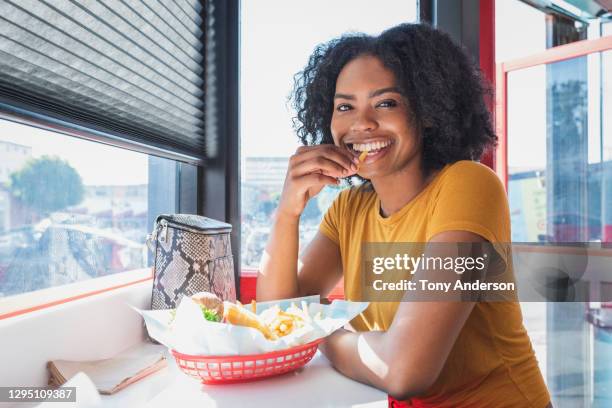 young woman eating in diner - batata frita francesa imagens e fotografias de stock