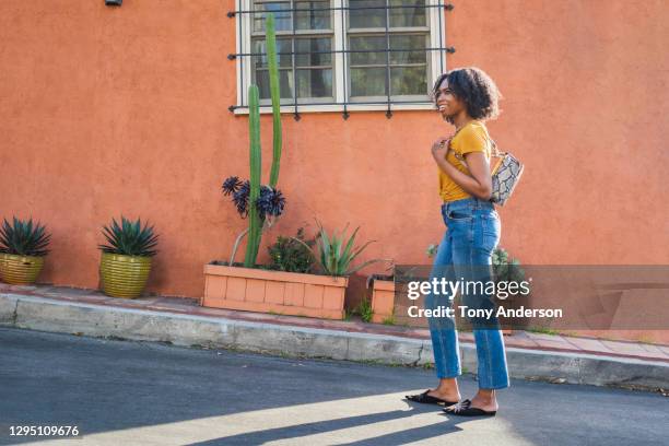 young woman walking on street - jeans neri foto e immagini stock