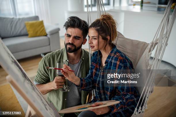 young couple painting together in the living room - house for an art lover stock pictures, royalty-free photos & images