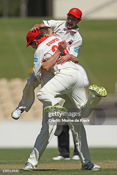 Tom Cooper and Kane Richardson of the Redbacks jump on team mate Peter George after he got the wicket of Simon Katich of the Blues during day two of...