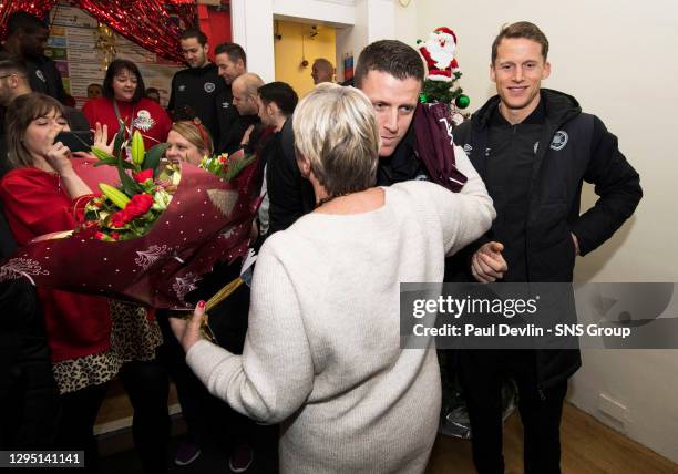 Hearts Captain Christophe Berra and Colin Doyle hands over gifts to retiring NHS worker Ishbel Proctor.