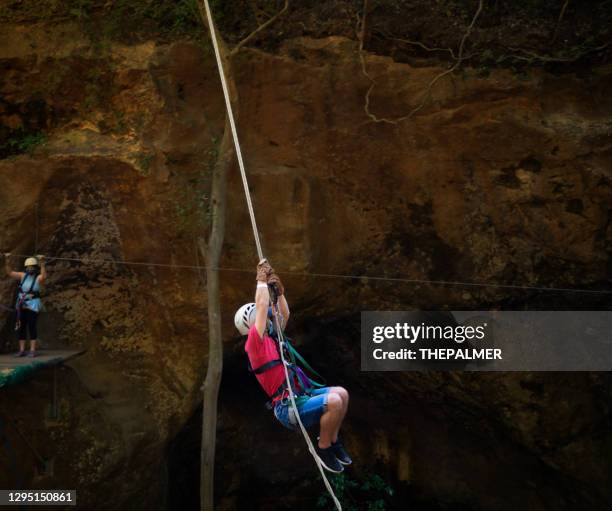 teen hanging from rope swing on canopy tour - costa rica zipline stock pictures, royalty-free photos & images