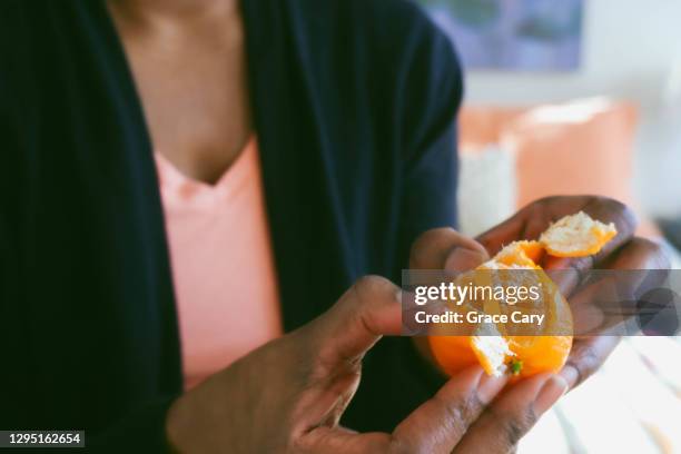 woman peels clementine - peeling food stock pictures, royalty-free photos & images