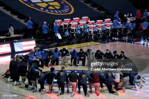 Members of the Denver Nuggets and the Dallas Mavericks kneel at center court for the playing of the National Anthem at Ball Arena on January 07, 2021...