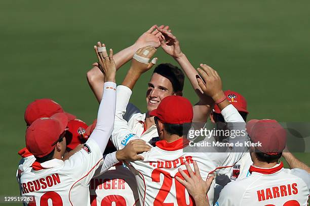 Peter George of the Redbacks is congratulated by team mates after getting his fifth wicket during day two of the Shieffield Shield match between the...