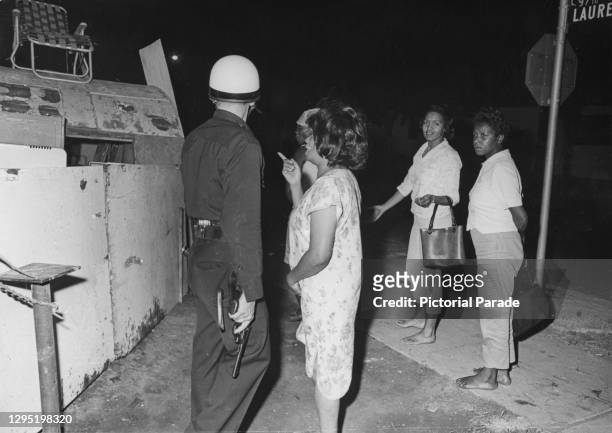 Group of women speaking to a State Trooper, who is holding his handgun, on the streets following the riots in the Watts neighbourhood of Los Angeles,...