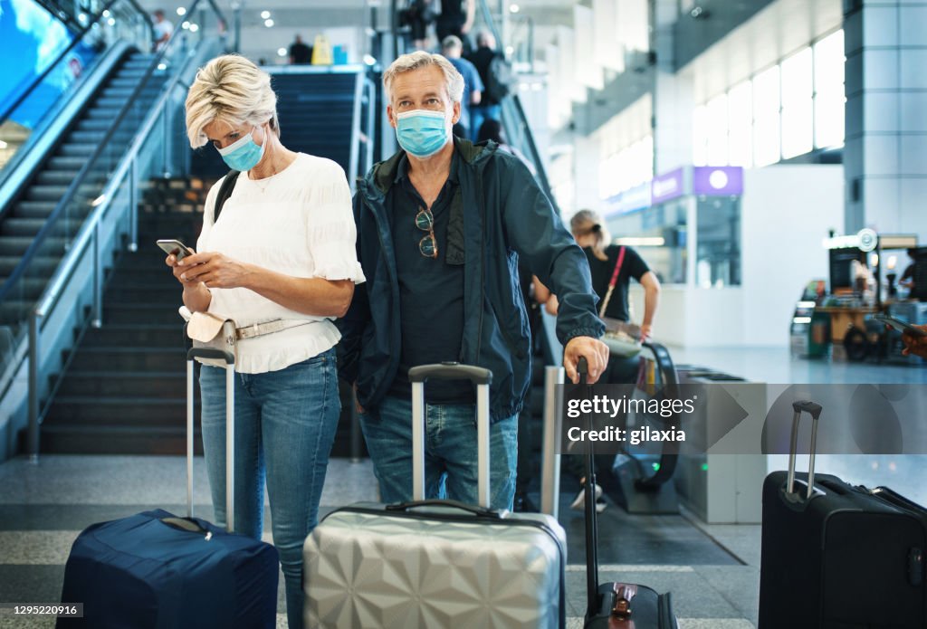 Middle aged couple at an airport during coronavirus pandemic.