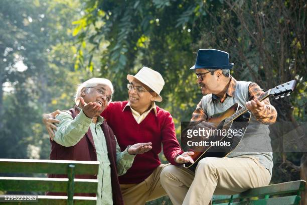 three senior men playing guitar and having fun at park - ethnicity stock pictures, royalty-free photos & images