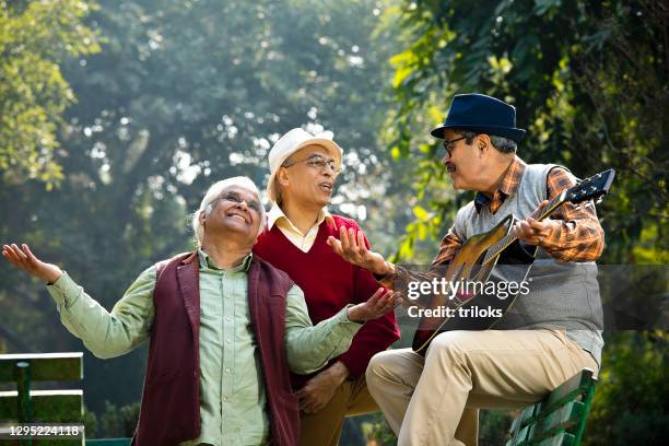 tre uomini anziani che suonano la chitarra e si divertono al parco - dancer india foto e immagini stock