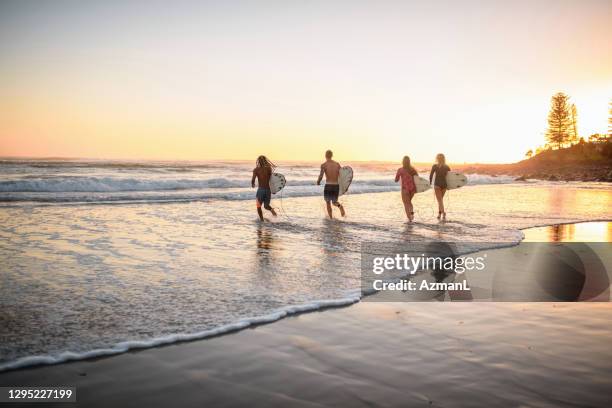 gold coast surfen vrienden lopen in het water bij dawn - gold coast australia stockfoto's en -beelden