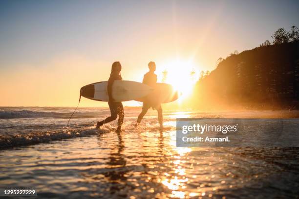 male gold coast surfers coming out of water at dawn - beach holding surfboards stock pictures, royalty-free photos & images