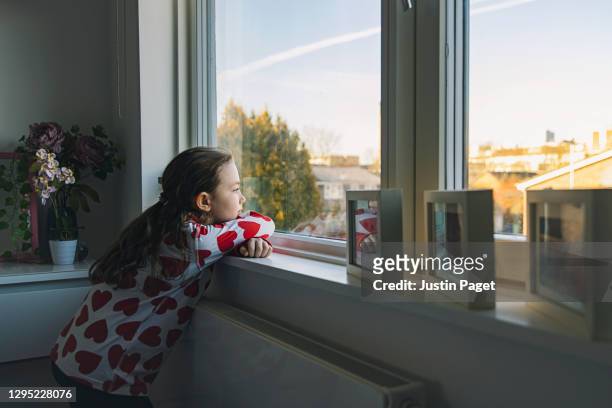 young girl looking out of bedroom window - staring stockfoto's en -beelden