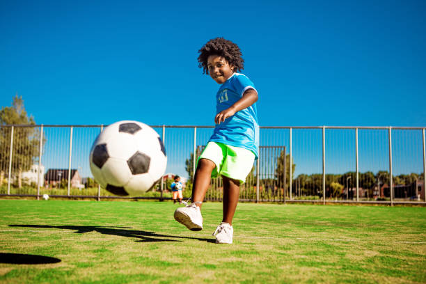 beautiful young black boy training on the football pitch - kids stock pictures, royalty-free photos & images