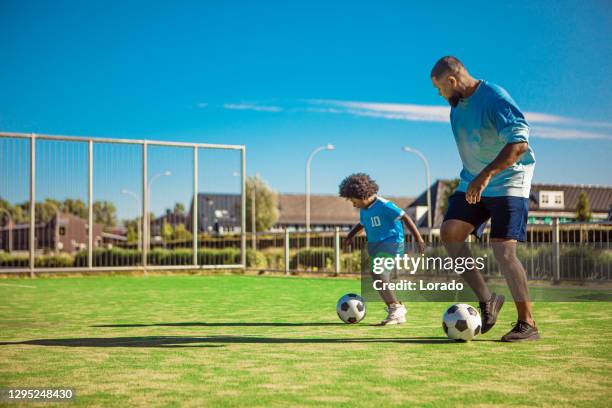 svart far och ung son utbildning på fotbollsplanen - football pitch bildbanksfoton och bilder