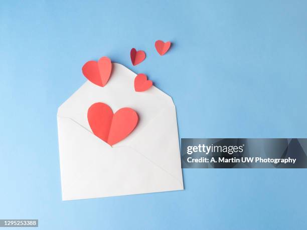 envolope and red paper hearts isolated on blue background - san valentino festività pubblica foto e immagini stock