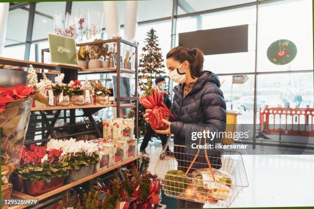 giovane donna che fa shopping per cibo sano al supermercato con maschera protettiva - christmas decorations in store foto e immagini stock
